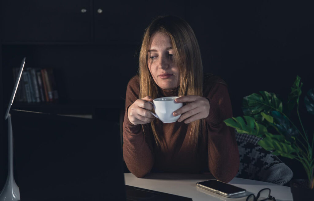 lady in a dark room, drinking a cup of coffee at night